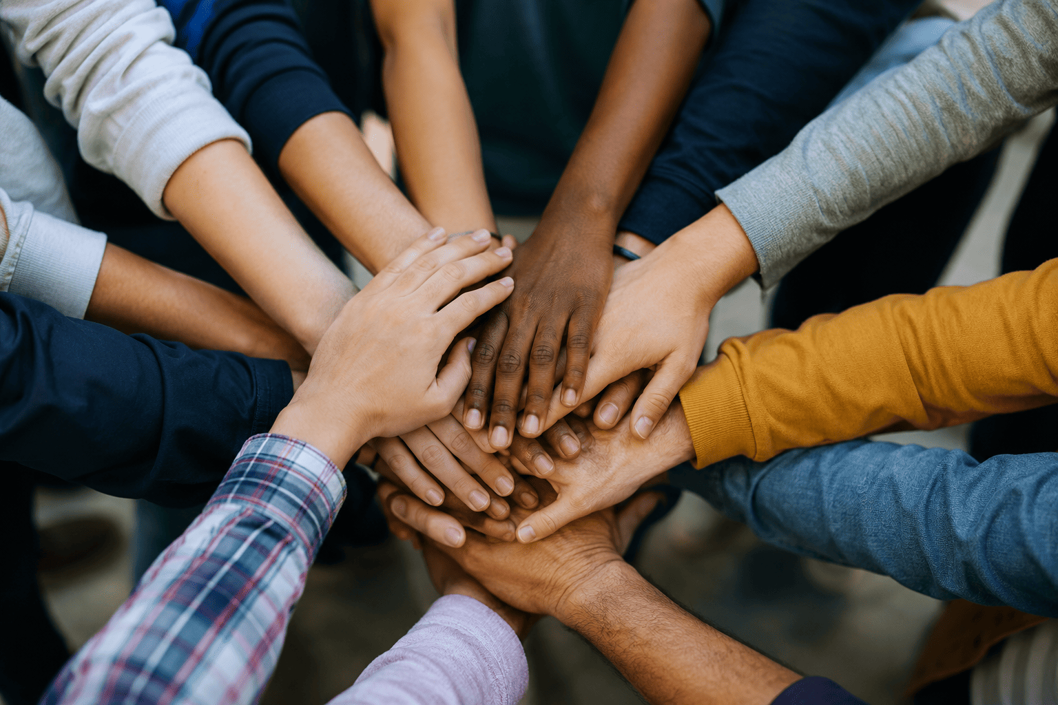 Many hands joined together in the centre of a circle