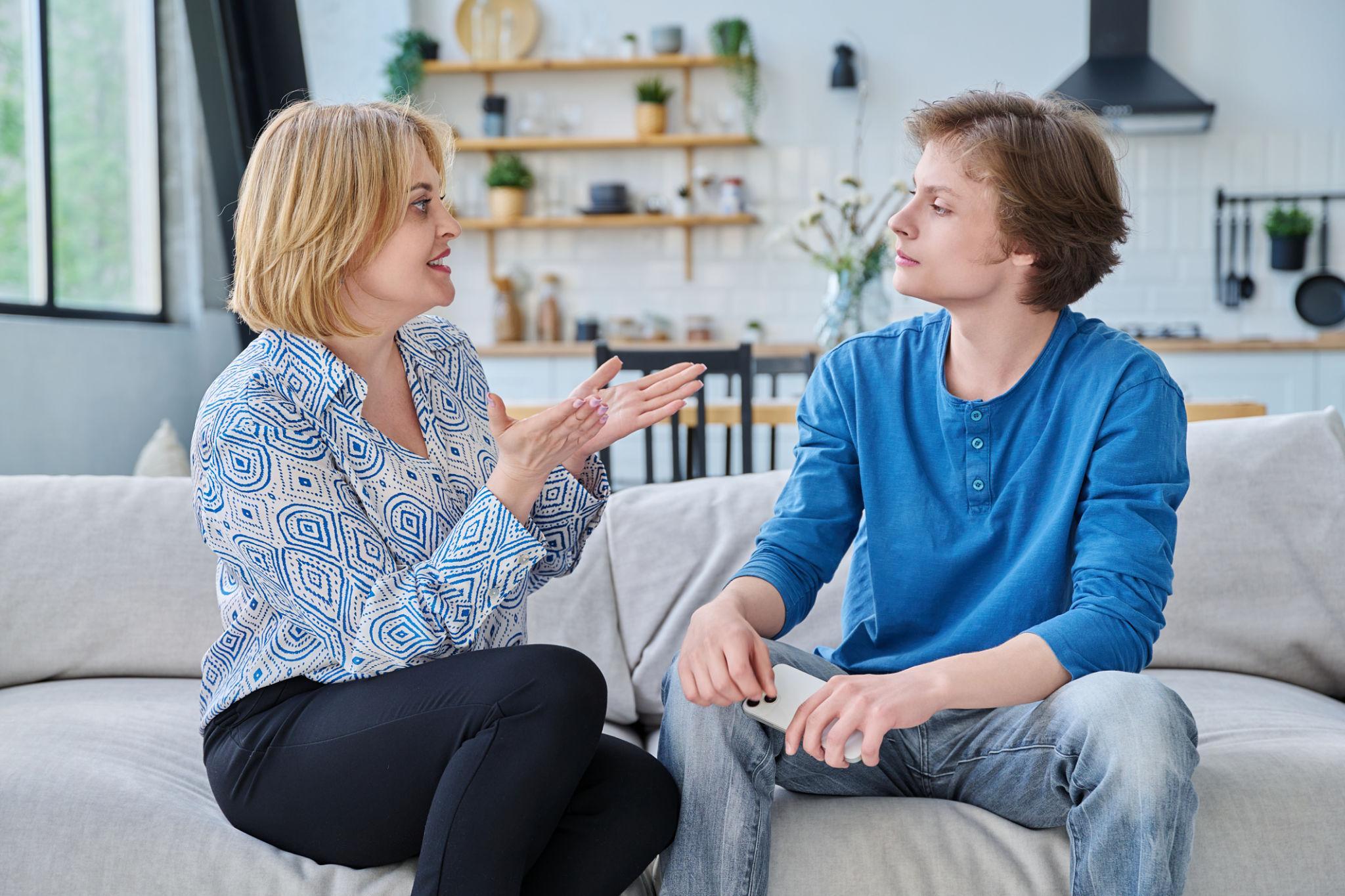 An adult in conversation with a teenager at home